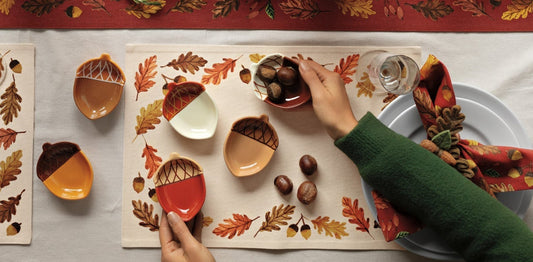 Decorative Thanksgiving table setting with candles, pumpkins, and autumn-themed place mats.