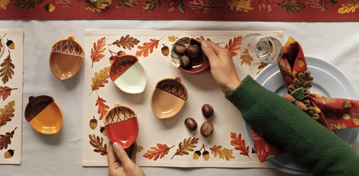Decorative Thanksgiving table setting with candles, pumpkins, and autumn-themed place mats.
