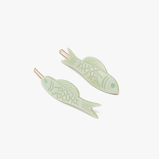 A pair of green fish-shaped sardine barrettes on a white background