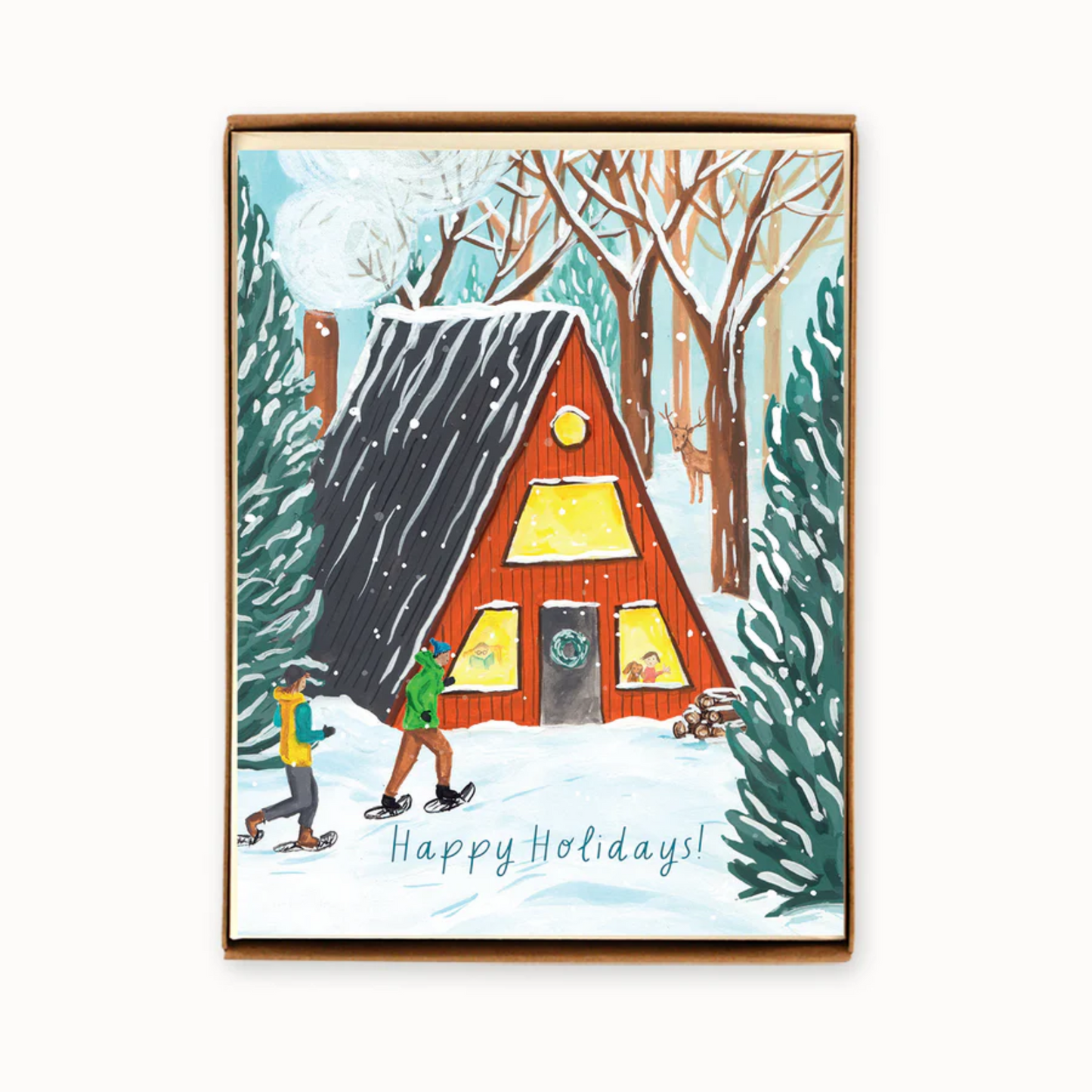 A boxed holiday greeting card featuring an illustration of an A-frame cottage in a snowy landscape with people outside.