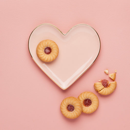 Heart-shaped plate with cookies on a pink background